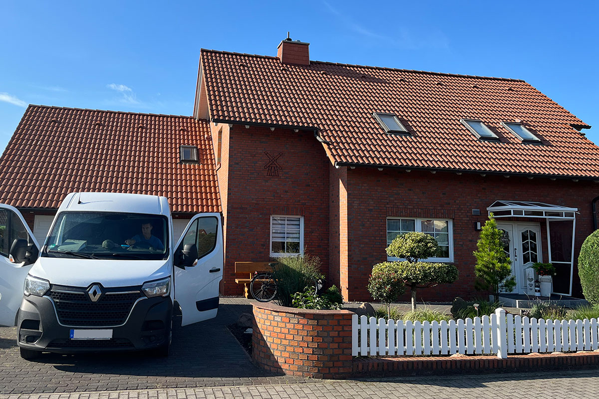 Haus mit Ziegeldach vor der Dachbeschichtung, Transporter in Einfahrt